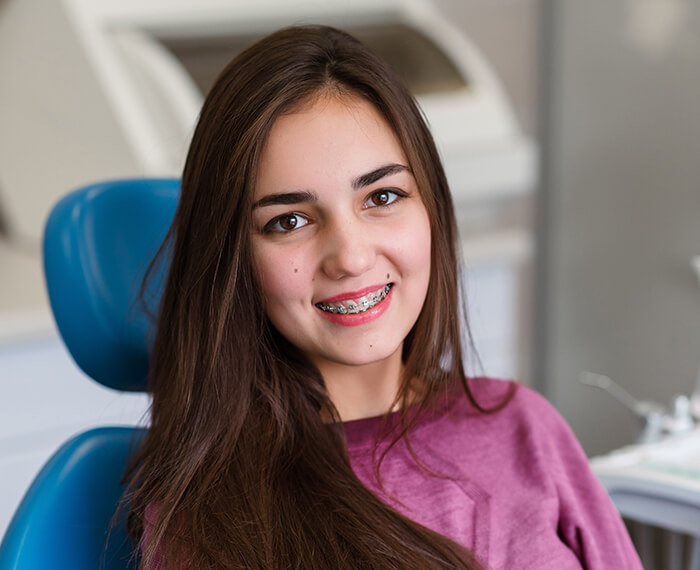 Teenage girl with braces smiling in dental chair