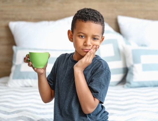 Young boy holding his cheek in pain