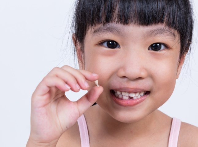 Young girl holding her extracted tooth