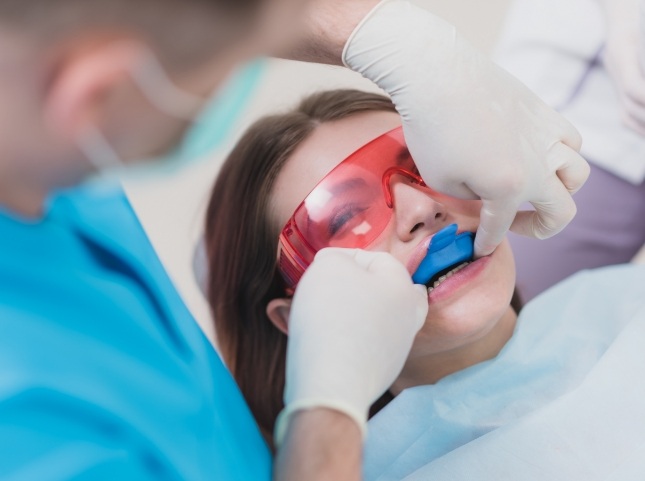 Teenage girl in dental chair with fluoride trays on her teeth