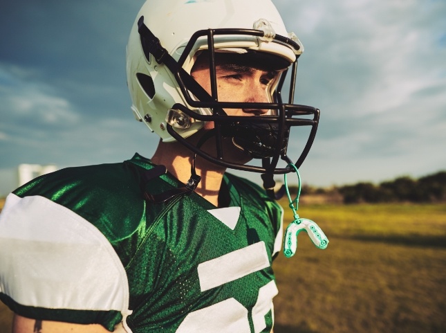 Football player with mouthguard hanging from his helmet