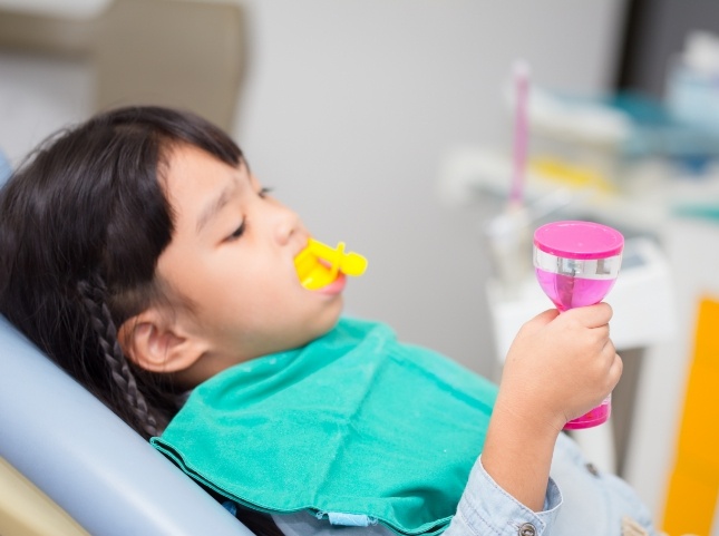 Child in dental chair with fluoride trays on their teeth