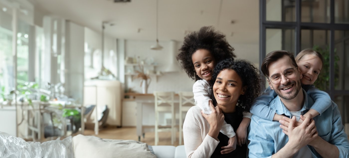 Family of four smiling in their living room