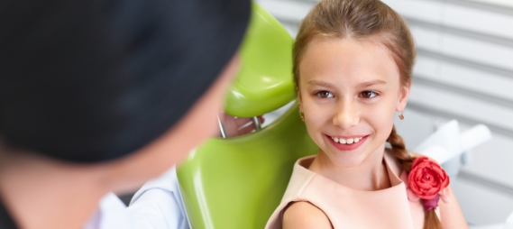 Young girl in dental chair smiling at her dentist