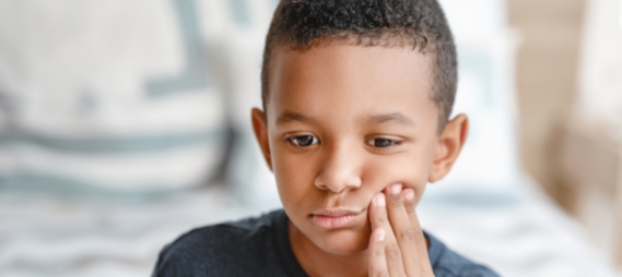 Young boy touching his cheek in pain