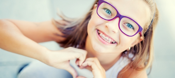 Young girl with braces making a heart shape with her hands