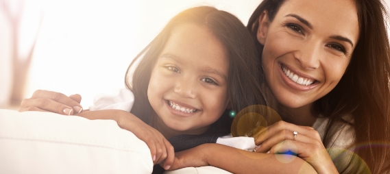 Smiling mother and daughter sitting on couch