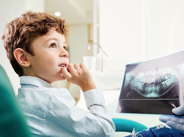 Curious boy looking at dental X-ray with his dentist
