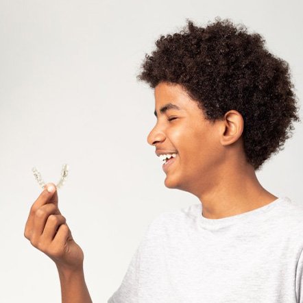 Kid smiles at Invisalign tray