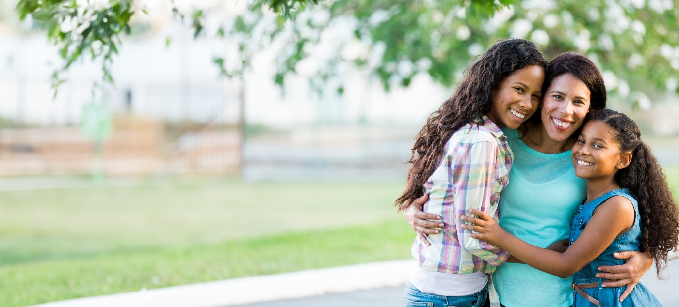 Woman and two daughters smiling outdoors after visiting pediatric dental team in Dublin