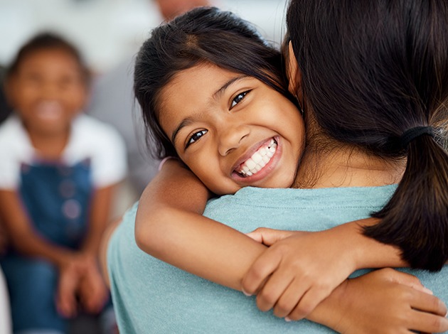 Young girl smiling while hugging her mom
