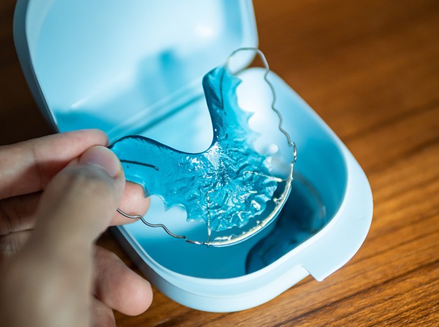 Person lifting their retainer from its case
