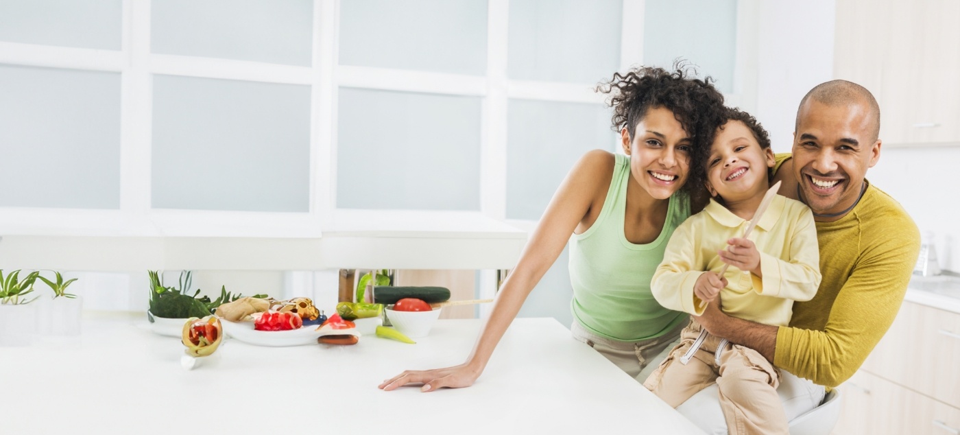 Family of three smiling in their kitchen