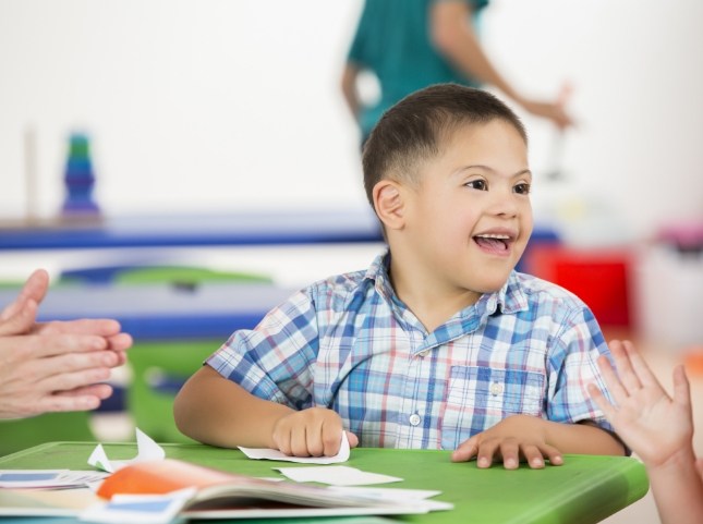 Young boy smiling while sitting at table with papers