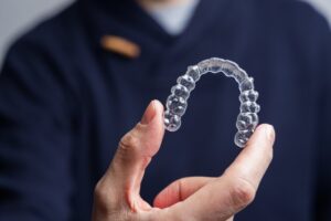 Dentist holding Invisalign close up in foreground.