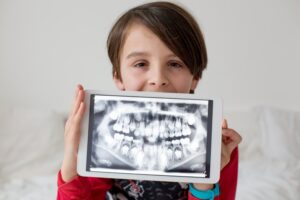 Child holding a tablet with their dental X-rays